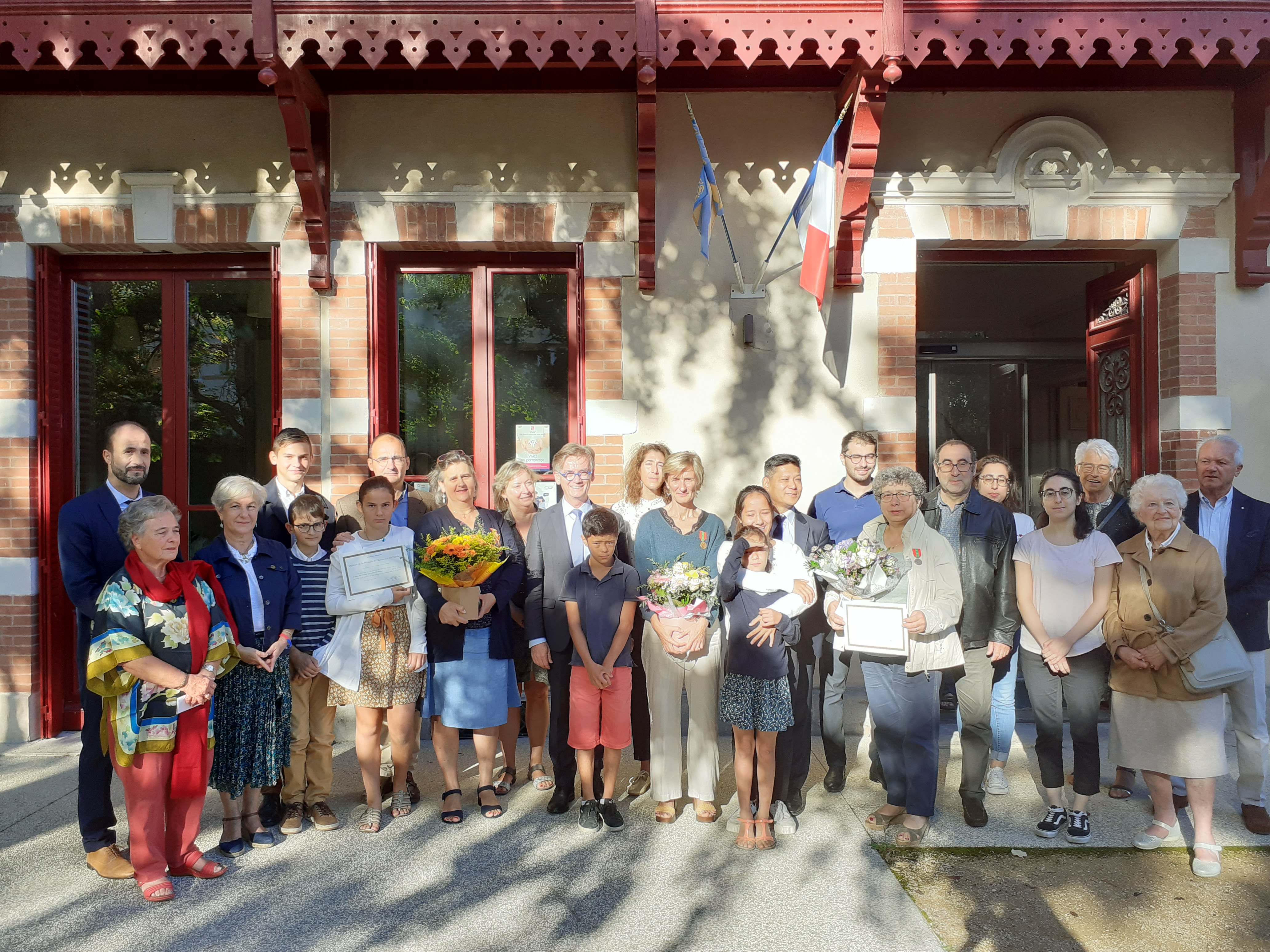 Groupe devant un bâtiment, avec bouquets et diplôme